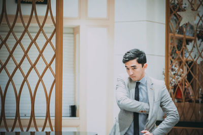 Portrait of businessman standing against house
