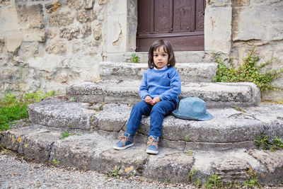 Little handsome baby boy sitting on ancient stone stairs outdoor