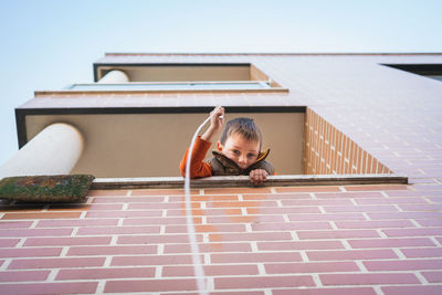 Bottom view of a boy holding a rope from the balcony.