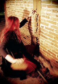 Midsection of woman holding umbrella against wall