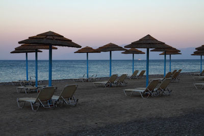 Deck chairs on beach against clear sky