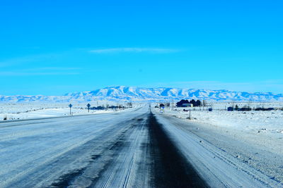 Tire tracks on snow landscape against blue sky