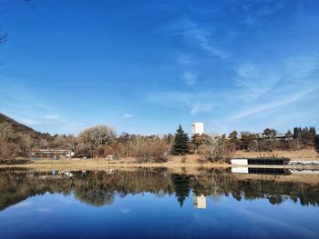 Reflection of building in lake against blue sky