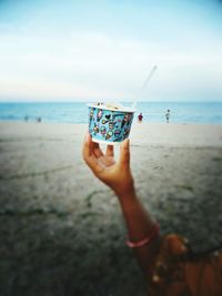 Close-up of woman holding ice cream on beach