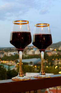 Pair of wine glasses on the balcony with blurry city evening view in the backdrop