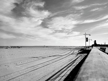 Railing by beach against cloudy sky at jacob riis park