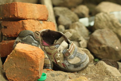 Close-up of baby booties by bricks on rock