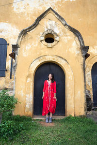 Full length of woman standing by building