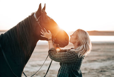 Woman with horse standing at beach