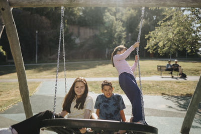 Siblings having fun swinging on swing on playground