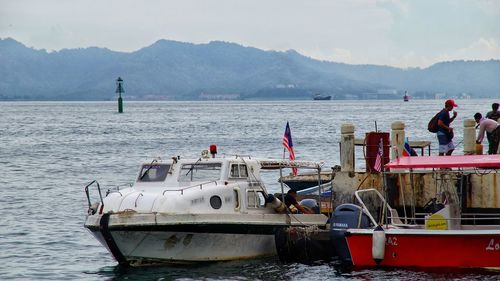 Fishing boats moored in sea against sky