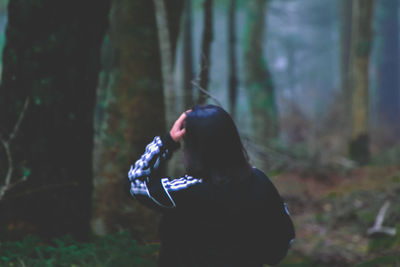 Man holding umbrella while standing on land in forest