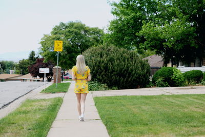 Rear view of woman walking on road amidst trees