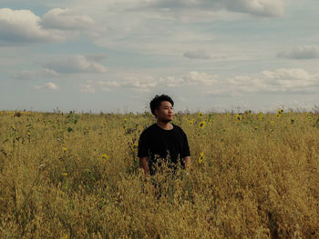 Young man standing on field against sky