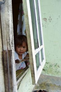Portrait of cute girl peeking through window