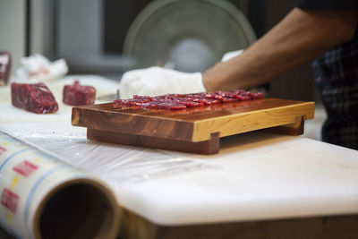 Midsection of man cutting meat in kitchen