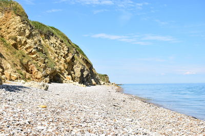 Rock formation on beach against sky