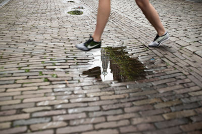 Low section of woman walking on cobblestone street