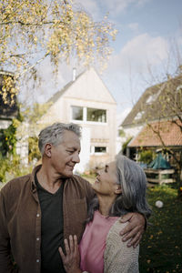 Happy senior couple in garden of their home in autumn