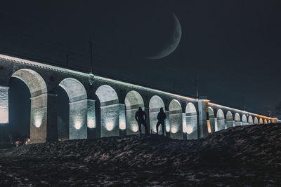 Low angle view of illuminated bridge against sky at night