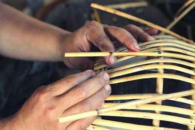 Midsection of man making wicker basket