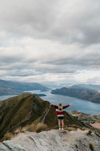 Rear view of woman standing on mountain against sky