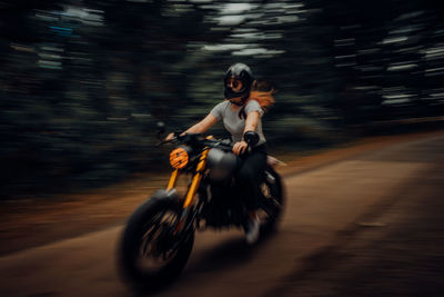 Rear view of man riding motor scooter on road