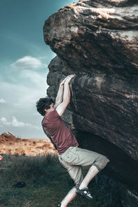 Man standing on rock against sky