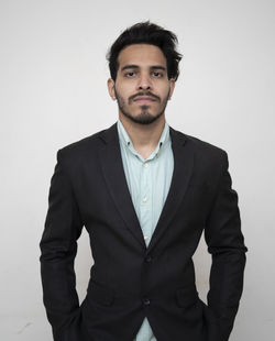 Portrait of young man standing against white background