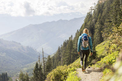 Rear view of female hiker with backpack walking against mountains