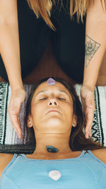 Therapist giving reiki treatment to woman with stones in the head