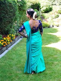 Rear view of young woman in sari standing on grassy field at park