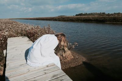 Woman standing on retaining wall by sea against sky