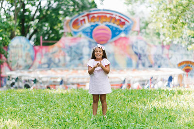 A cute little girl in the park is holding popcorn in her hands and smiling with a big smile