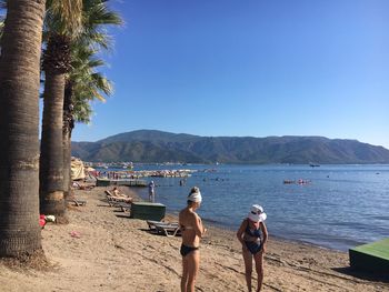 People on beach by sea against clear sky