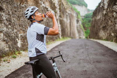 Side view of cyclist drinking water on road