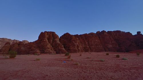 Rock formations on landscape against clear blue sky