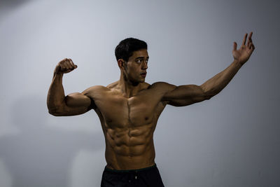 Shirtless muscular man standing against wall