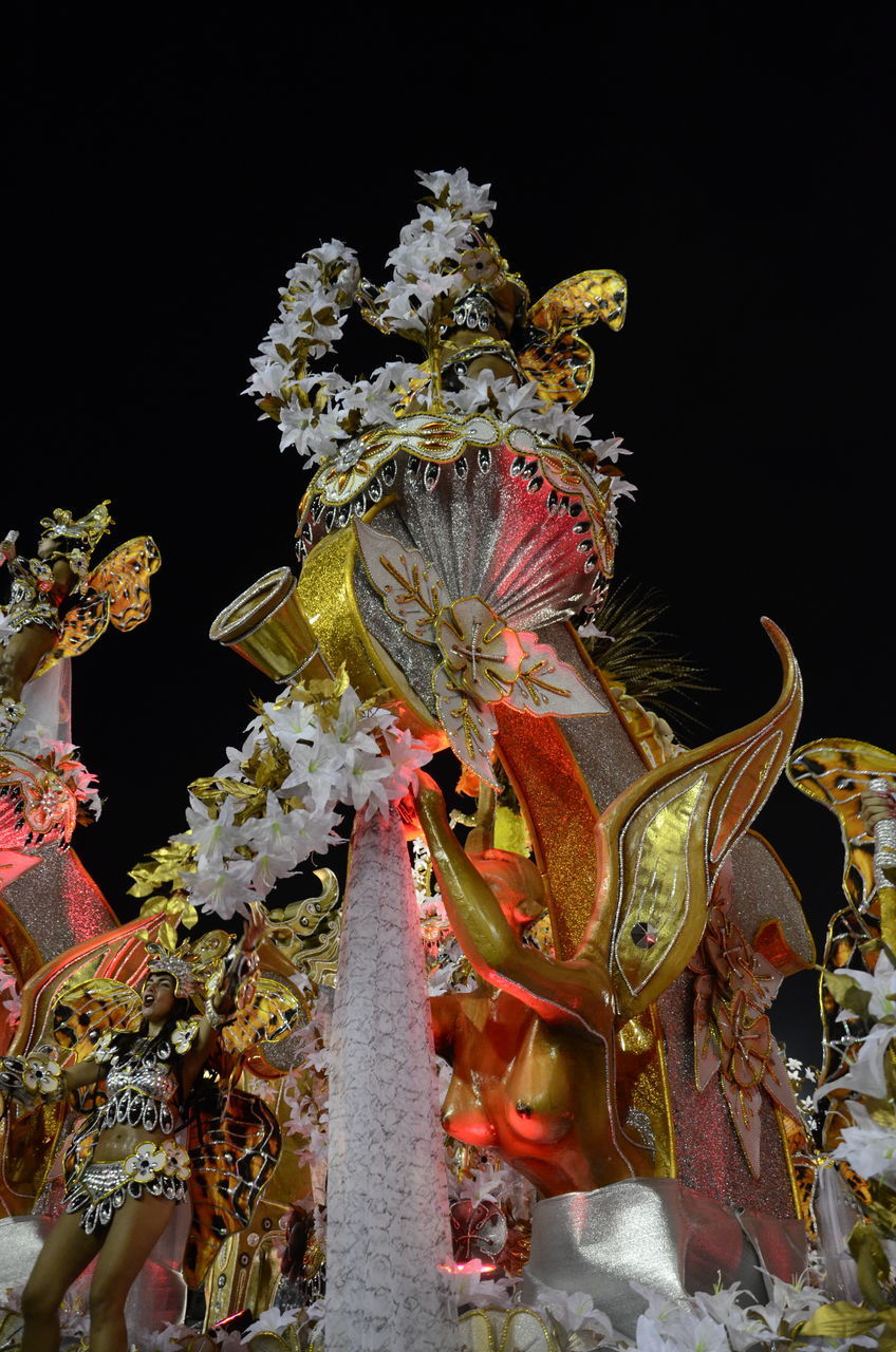 CLOSE-UP OF ILLUMINATED STATUE BY FLOWERS