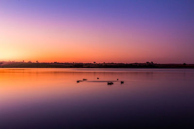 Scenic view of lake against clear sky during sunset