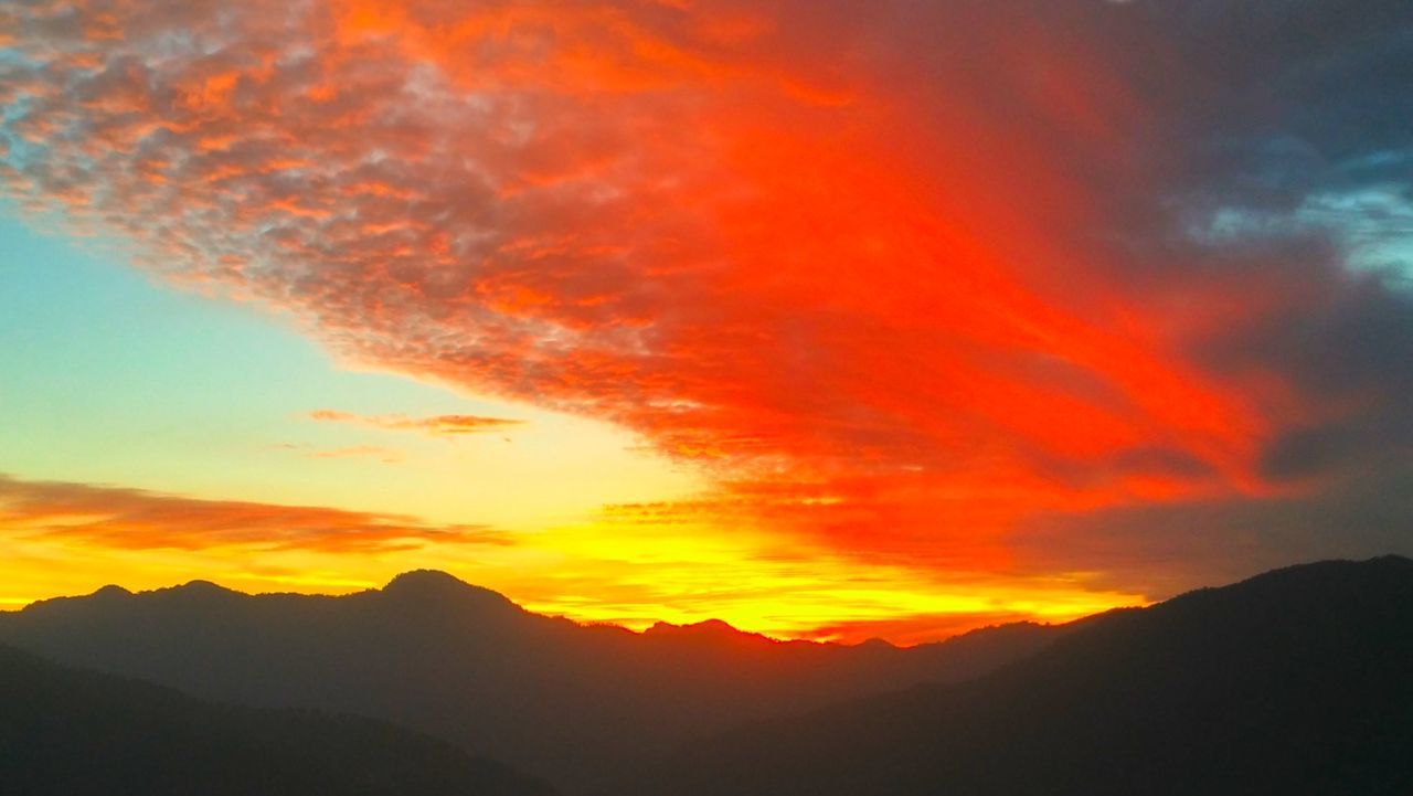 SILHOUETTE MOUNTAINS AGAINST ORANGE SKY