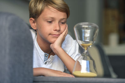 Boy looking at hourglass at home 
