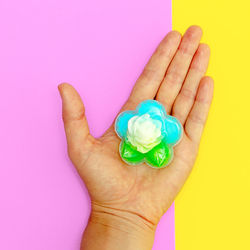 Close-up of hand holding colored pencils over pink background