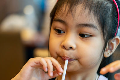 Cute girl drinking milkshake at restaurant