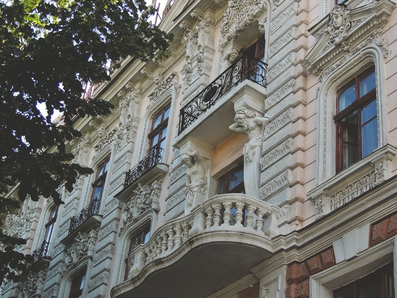 architecture, built structure, low angle view, building exterior, no people, tree, building, day, plant, window, nature, balcony, outdoors, residential district, city, sunlight, lighting equipment, history, growth, sky, architectural column, ornate