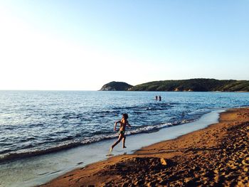 Full length rear view of boy running on beach