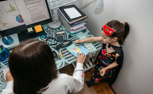 High angle view of woman assisting daughter in drawing 