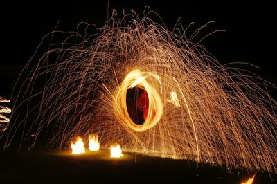 Midsection of man spinning burning wire wool at night