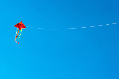 Low angle view of kite flying against clear blue sky