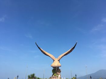 Low angle view of horse sculpture against blue sky